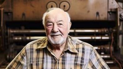 senior devant une ancienne machine d'imprimerie 