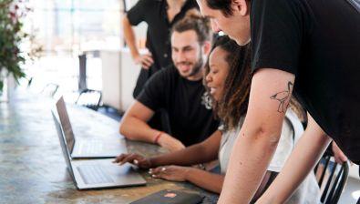 Une femme et deux hommes regardent un écran d'ordinateur